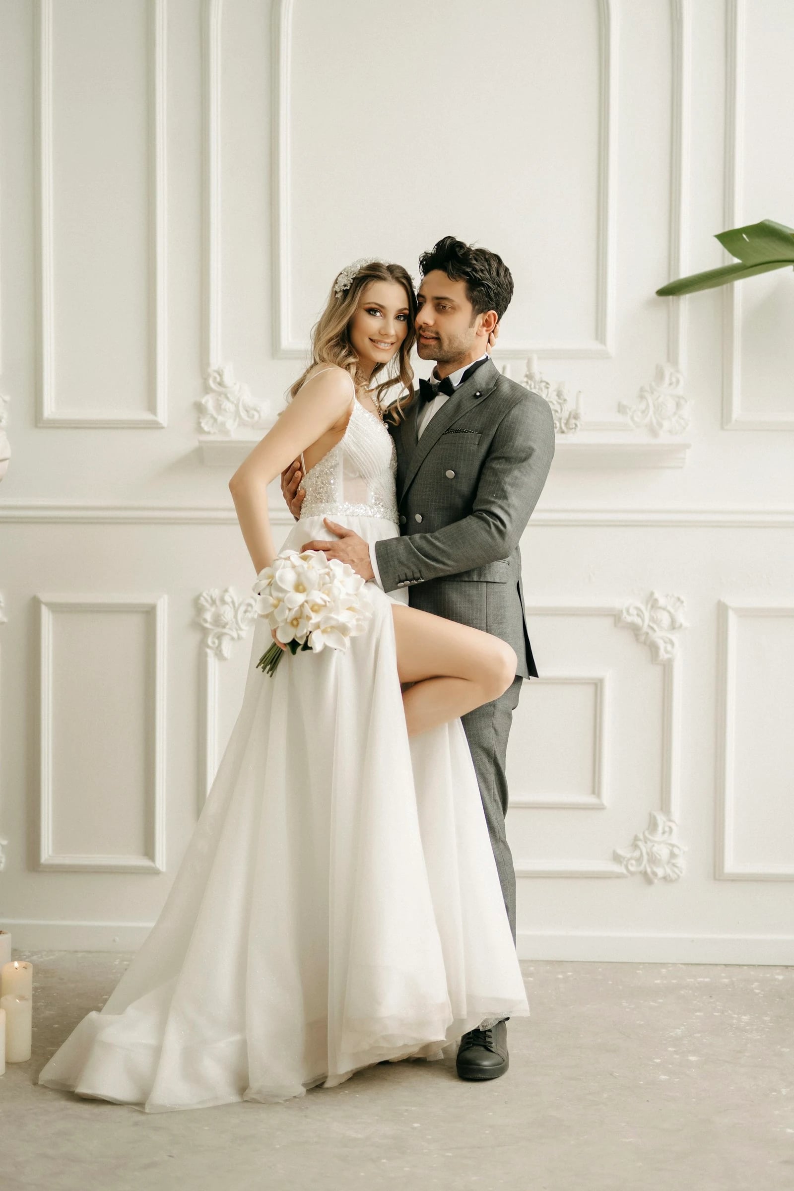 Pasangan pengantin dengan buket putih di ruangan klasik yang terang